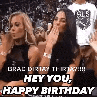 two women are sitting in the stands at a basketball game and one is blowing a kiss .