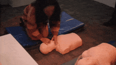 a woman is practicing on a mannequin with her hands on it 's chest