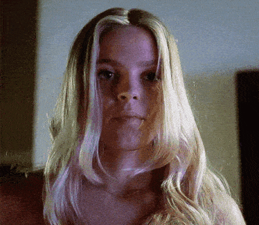 a woman with long blonde hair looks at the camera with a serious look on her face