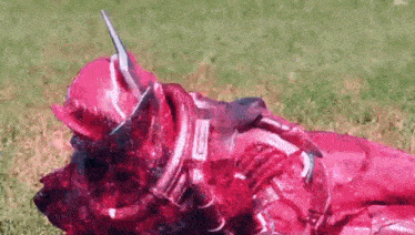 a person in a red superhero costume is laying in the grass .