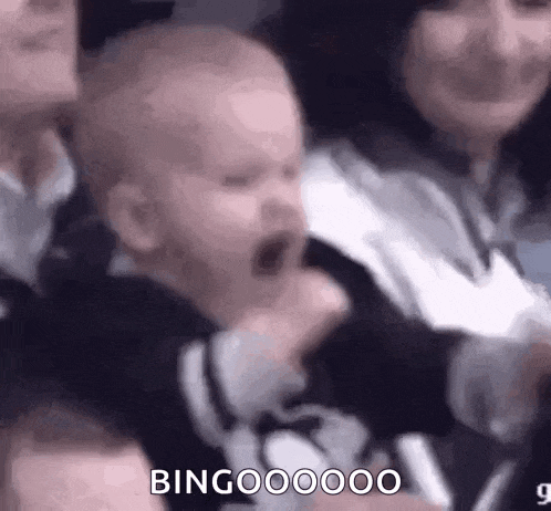 a baby is yawning while being held by a woman in a crowd .