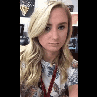 a woman with blonde hair and a lanyard around her neck is making a face .