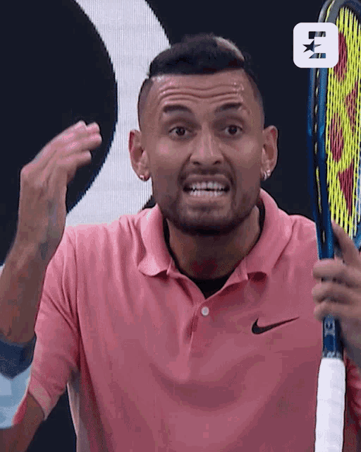 a man in a pink shirt is holding a tennis racket