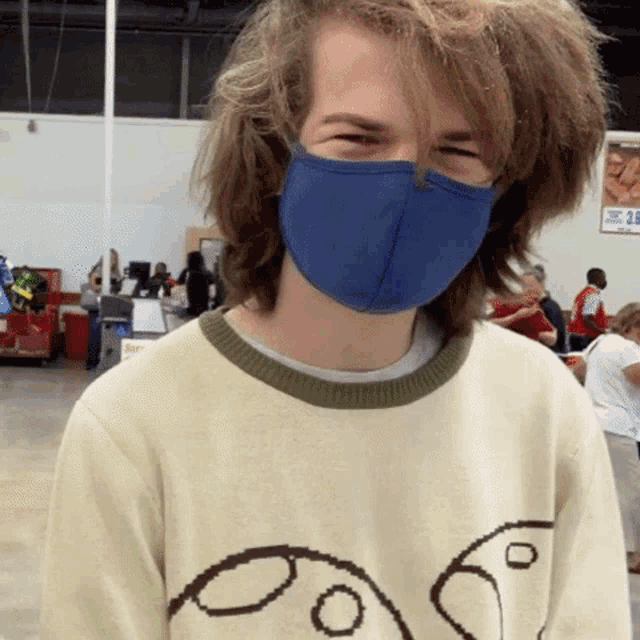 a young man wearing a blue mask and a sweater with a face on it