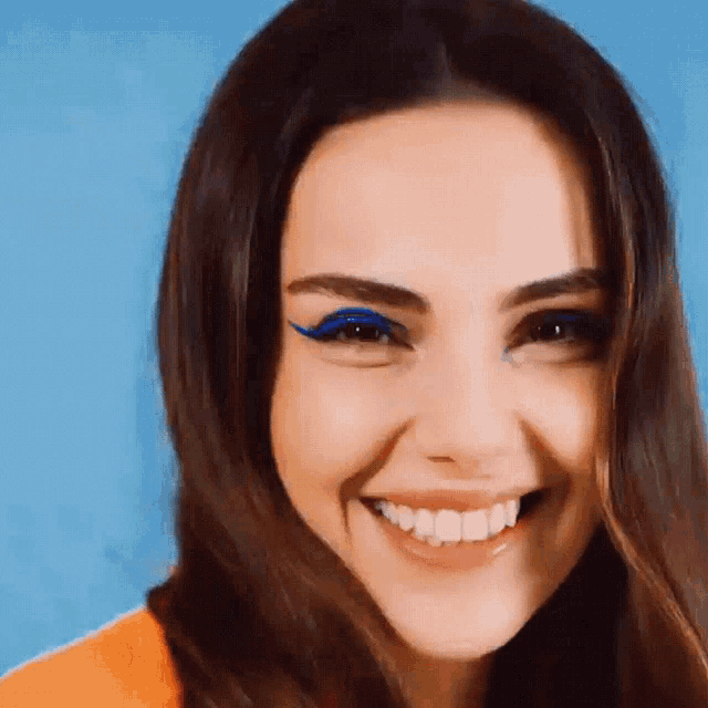 a woman with blue eyeliner on her eyes smiles