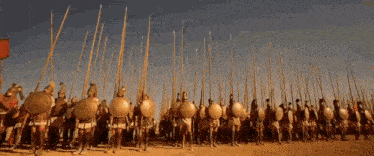 a large group of soldiers with shields and spears standing in a field