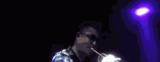 a man playing a trumpet in a dark room