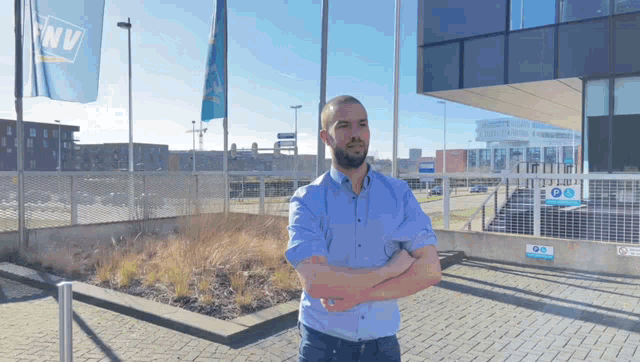 a man with his arms crossed stands in front of a building that says nv on it