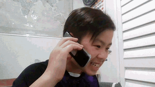 a young boy talking on a cell phone with a map of the world in the background