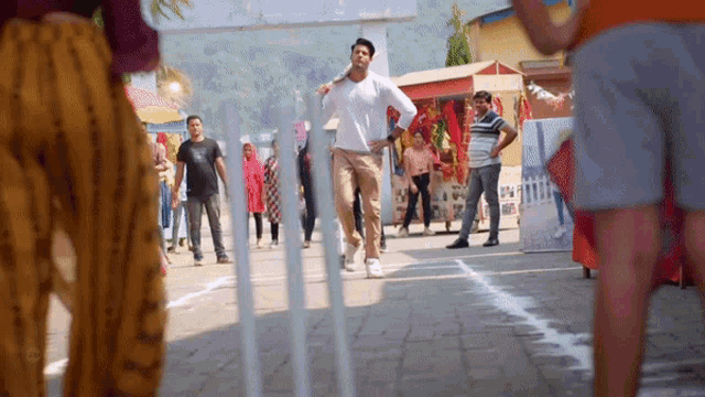 a man in a white shirt and khaki pants is running down a street