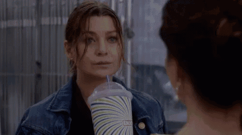 a woman in a denim jacket is holding a drink in her hand .