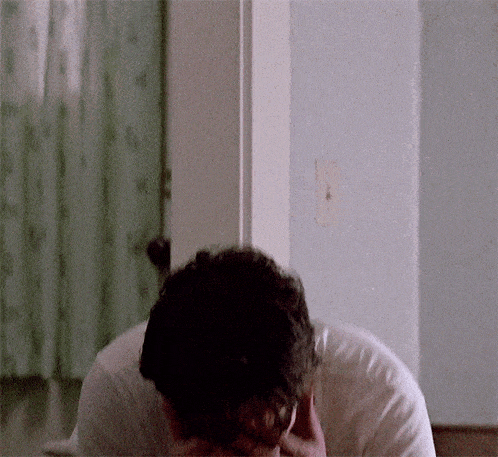 a man in a white shirt is laying down with his head in his hands