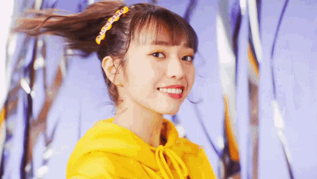 a close up of a woman wearing a yellow hoodie and a headband .