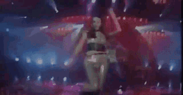 a woman is dancing on a stage in a dark room with purple lights .