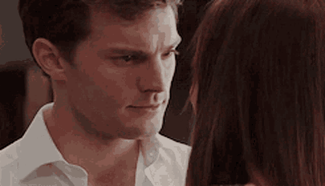 a man in a white shirt is looking at a woman with red hair .