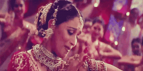 a woman in a red and gold dress is dancing in front of a crowd of people .