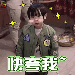 a little boy in a green jacket is standing in a room with chinese writing on it .