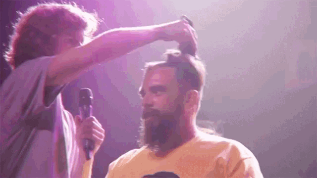 a man with a beard is getting his hair done by another man
