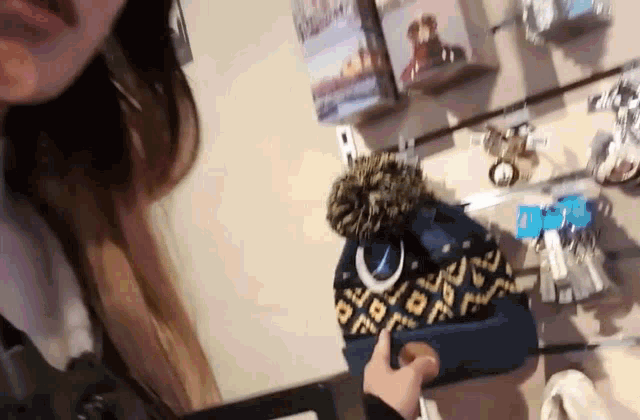 a woman is holding a blue hat with a crescent moon on it in a store