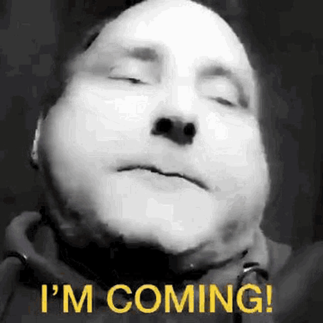a black and white photo of a man with his eyes closed and the words `` i 'm coming '' written on his face .