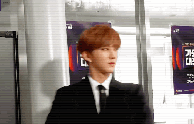 a man in a suit and tie stands in front of a sbs poster