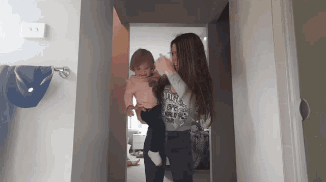 a woman holding a baby wearing a shirt that says ' one world one team '