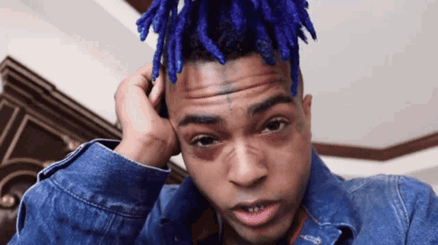 a man with blue dreadlocks is wearing a blue jacket