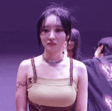 a woman with a tattoo on her arm is wearing a tank top and necklace