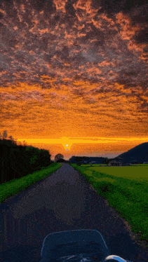 a view of a sunset from a motorcycle 's windshield