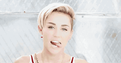 a woman with a shaved head is sticking her tongue out and making a funny face .