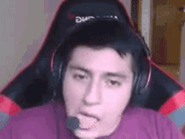 a man wearing headphones and a microphone is sticking his tongue out while sitting in a chair .