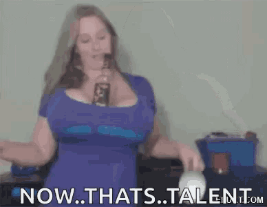 a woman with very large breasts is holding two cups and a bottle of alcohol .