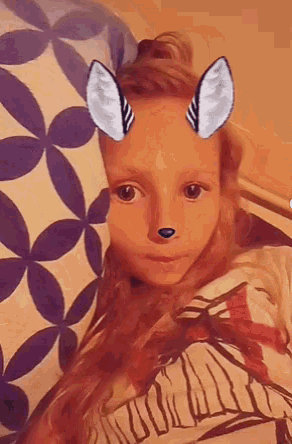 a little girl with a mask on her face looks at the camera