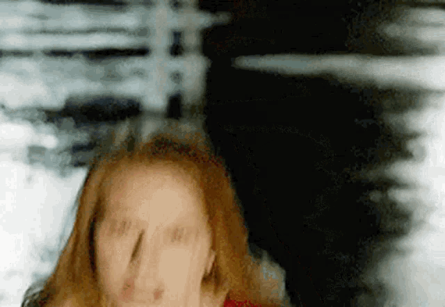 a woman with red hair is making a funny face with her eyes closed .