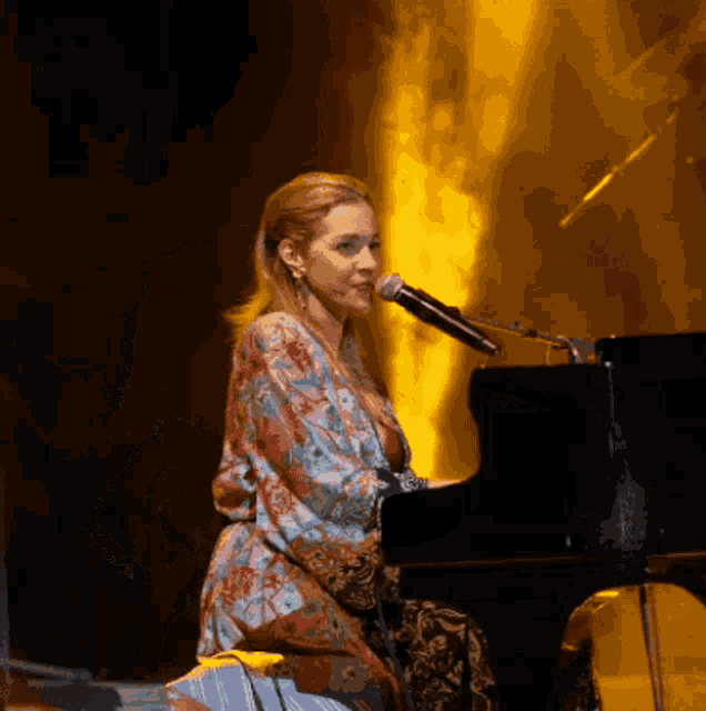 a woman is singing into a microphone while sitting at a piano