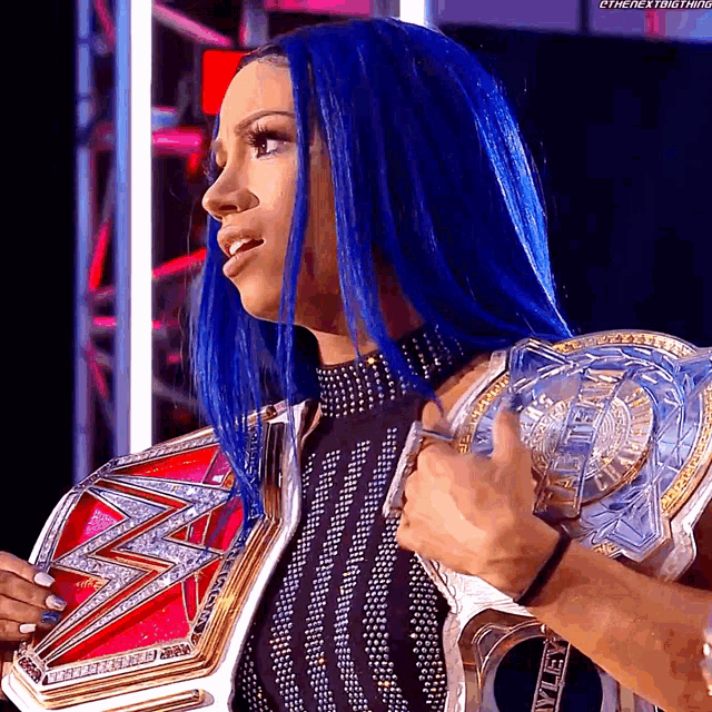 a woman with blue hair is holding a world heavyweight wrestling championship belt