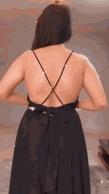 the back of a woman wearing a black dress with a crisscross strap .