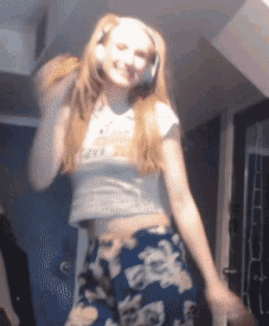 a woman wearing a crop top and floral shorts is dancing