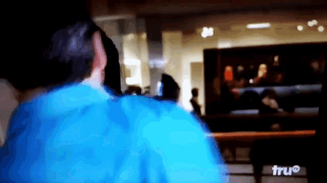 a man in a blue shirt is looking at a tv screen that says tru on it