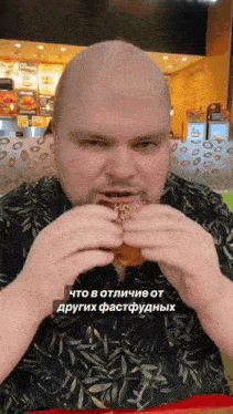 a bald man is eating a hamburger in a fast food restaurant in a foreign language ..