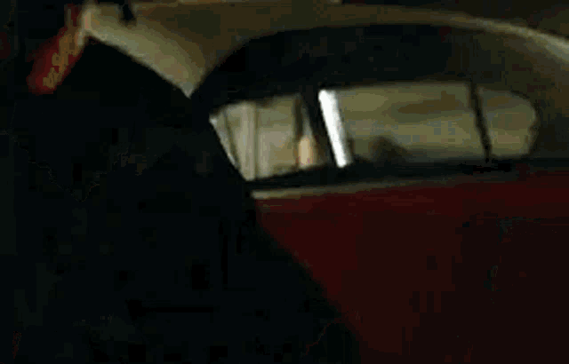 a red car is parked in a garage next to a black car .