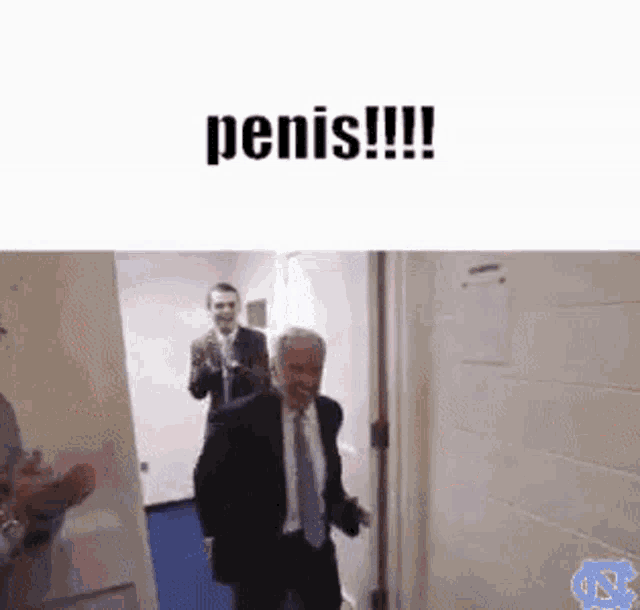 a man in a suit and tie is walking through a door with the words penis written on it .