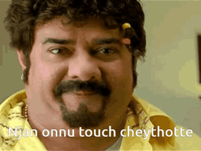 a man with a beard is wearing a yellow shirt and has the words " njan onnu touch cheythotte " below him