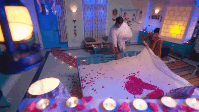 a man and a woman are making a bed with petals on it