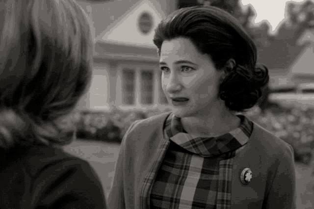 a woman in a plaid shirt has a button on her jacket that says ' a ' on it