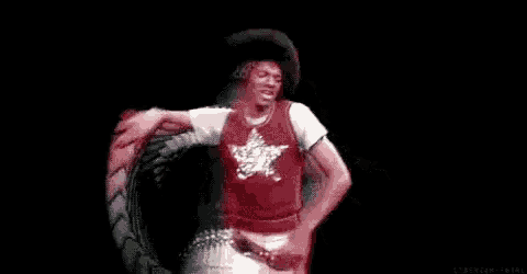 a man in a red shirt with a star on it is making a peace sign while dancing on a stage .