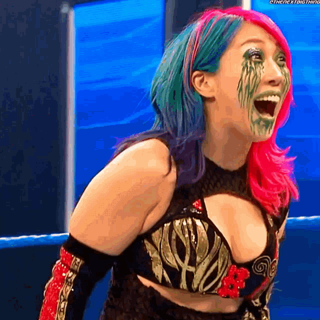 a female wrestler with pink and blue hair is smiling