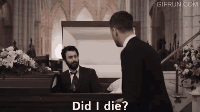 a man standing in front of a coffin with the words did i die written on it