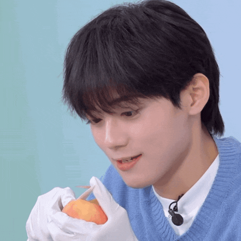 a young man in a blue sweater is holding an apple