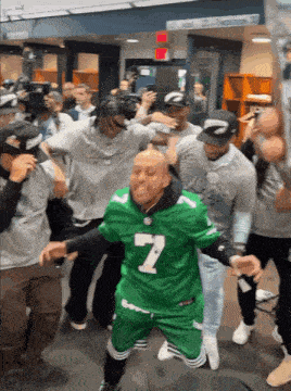 a man in a green jersey with the number 7 on it is surrounded by other people